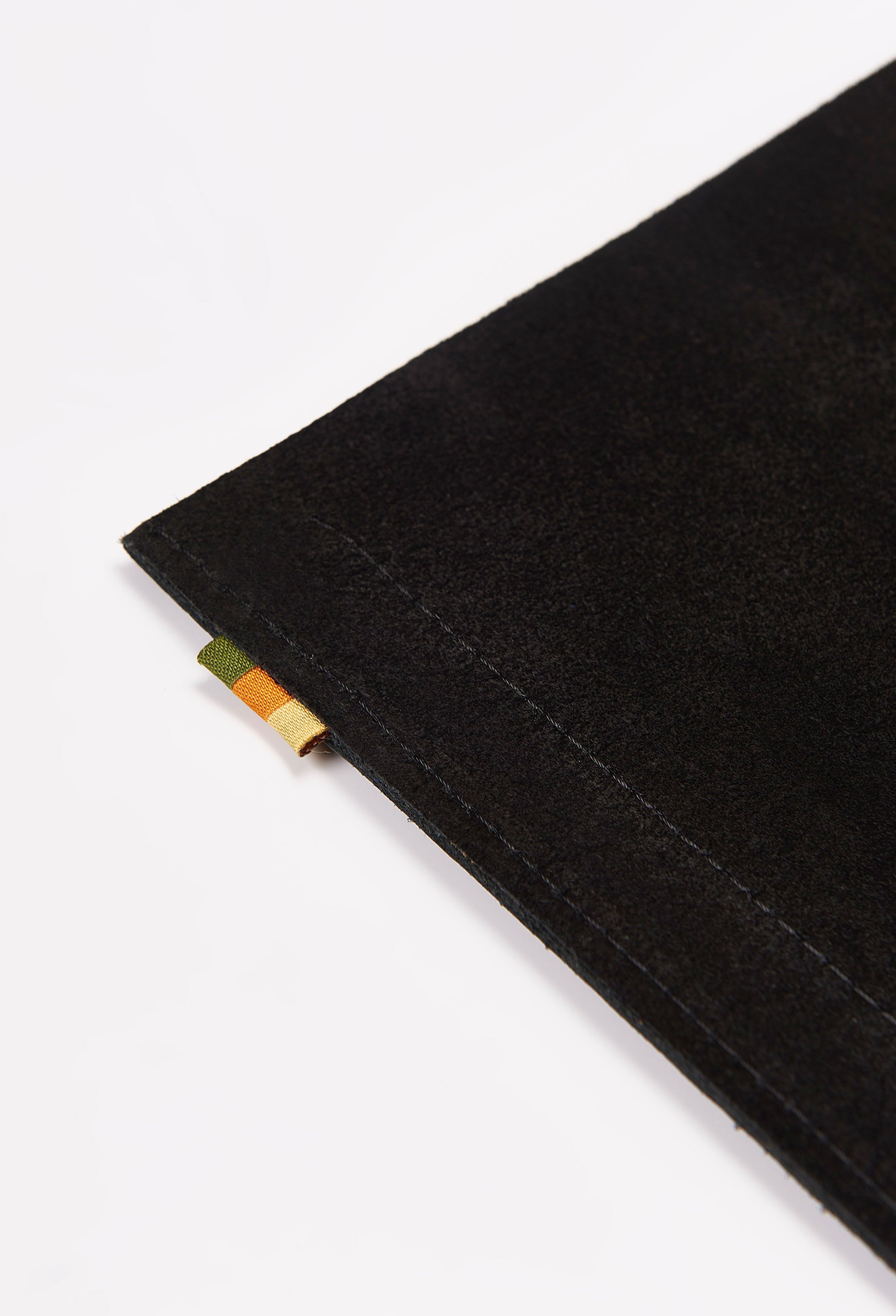 Partial photo of the rear of a black leather minimalist desk mat made of black suede leather with our Signature Grosgrain Loop Tab.