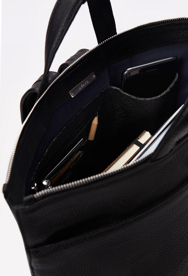 Interior of a Black Leather Tote Backpack that shows a zippered main compartment, a front zippered pocket and an internal cell phone pocket and card holder. 