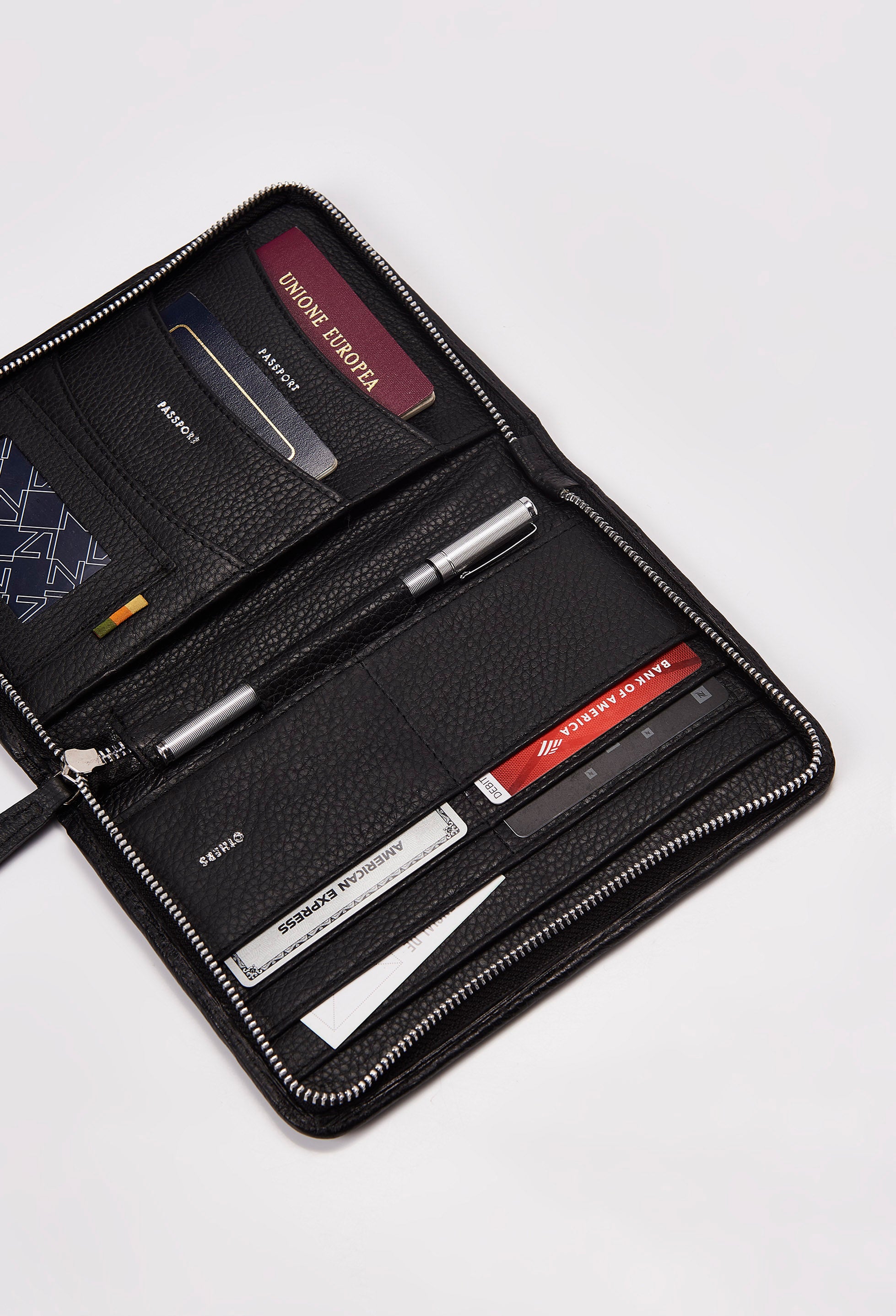 Interior of a Black Leather Passport Holder featuring labeled compartments for multiple passports, credit cards, personal cards and a pen.