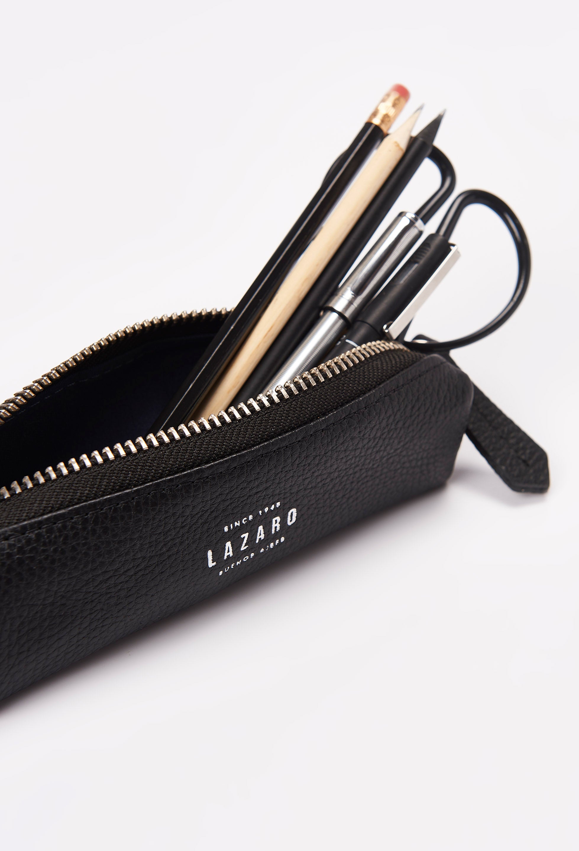 Interior of a Black Leather Pencil Case packed with pens, pencils and a scissor.