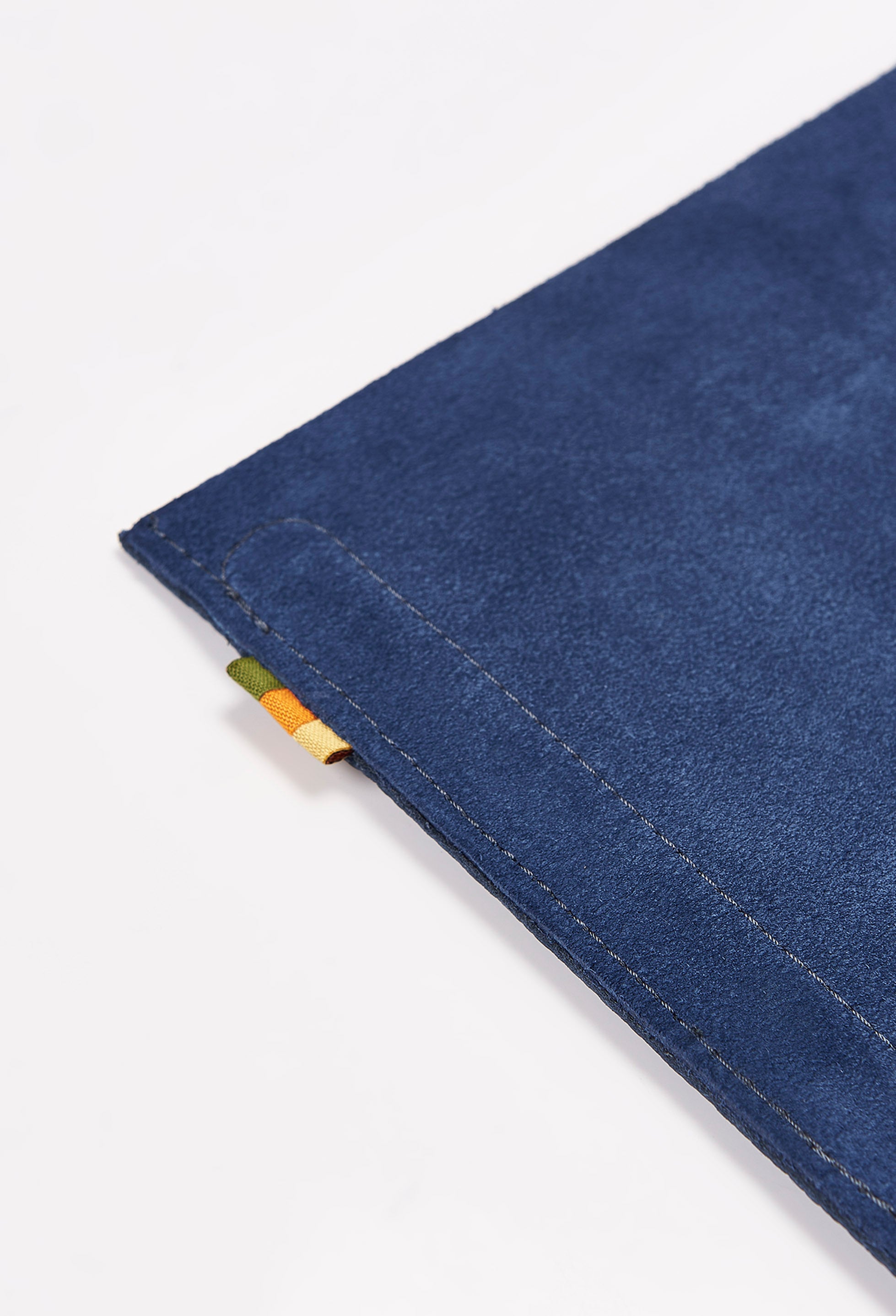 Partial photo of the rear of a blue leather minimalist desk mat made of blue suede leather with our Signature Grosgrain Loop Tab.