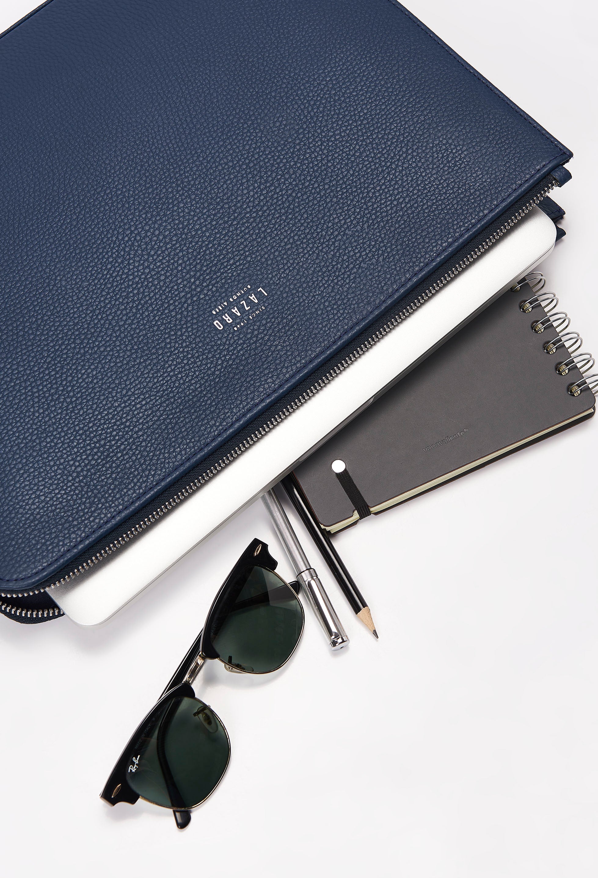 Partial photo of a Blue Leather Slim Computer Case that shows it can fit sunglasses, pencils and pens, notebooks and a computer.