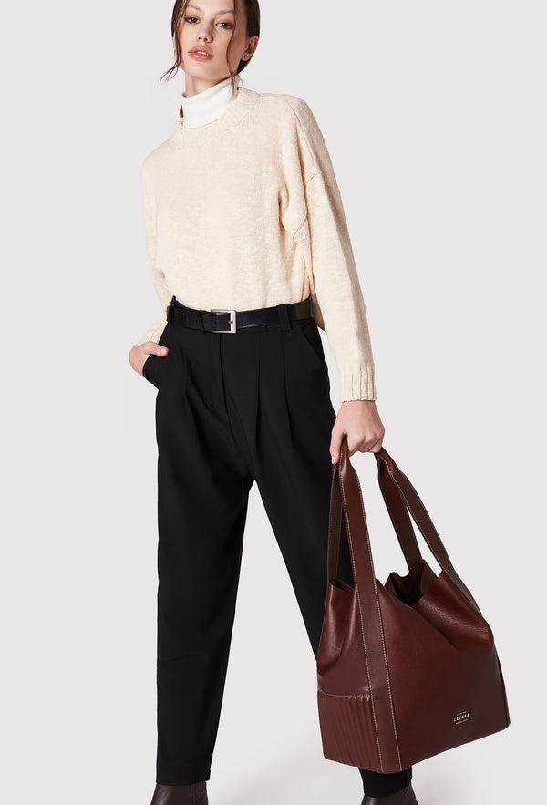 A model carries a sophisticated coffee leather bucket bag, showcasing its luxurious design. The bag features a unique needlework on its sides, adding to its elegant appeal. The model confidently displays the bag's size and craftsmanship while exuding a sense of style and sophistication.