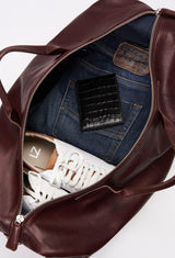 Interior of a Coffee Leather Duffel Bag packed with a Lazaro cardholder, clothes and a pair of shoes.