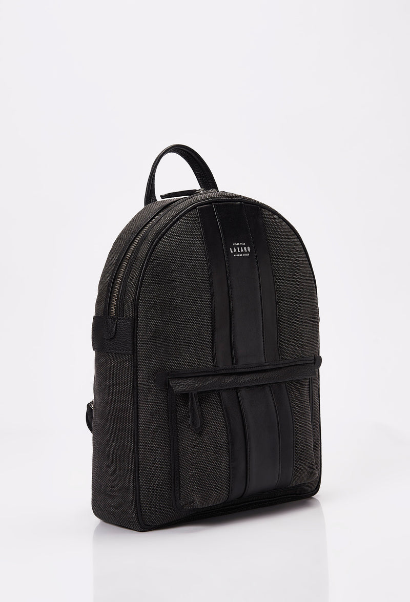 Side of a Lightweight Canvas Backpack made from distressed Panama canvas with Nappa leather trims in black. It has a main zippered compartment, the Lazaro logo and a front zippered pocket.