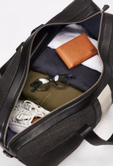 Interior of a Off White Large Canvas Duffel Bag packed with a Lazaro wallet, clothes, glasses and a pair of shoes.