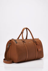 Side of a Tan Leather Duffel Bag with lock closure, Lazaro logo, leather id, leather handles and a detachable shoulder strap.