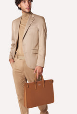 A model carries a sophisticated tan leather slim briefcase, showcasing its sophisticated design. The bag features a detachable shoulder strap, adding to its elegant appeal. The model confidently displays the bag's size and craftsmanship while exuding a sense of style and elegance.